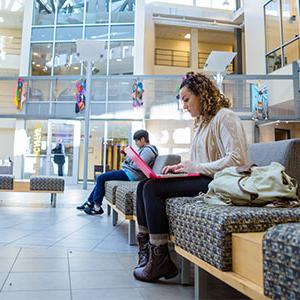 Student sitting in Parkhouse atrium working on laptop